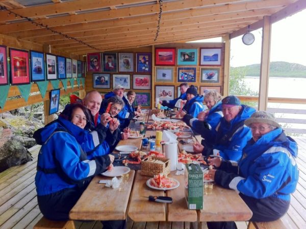 Tourists eat the king crab they caught themselves on the king crab safari